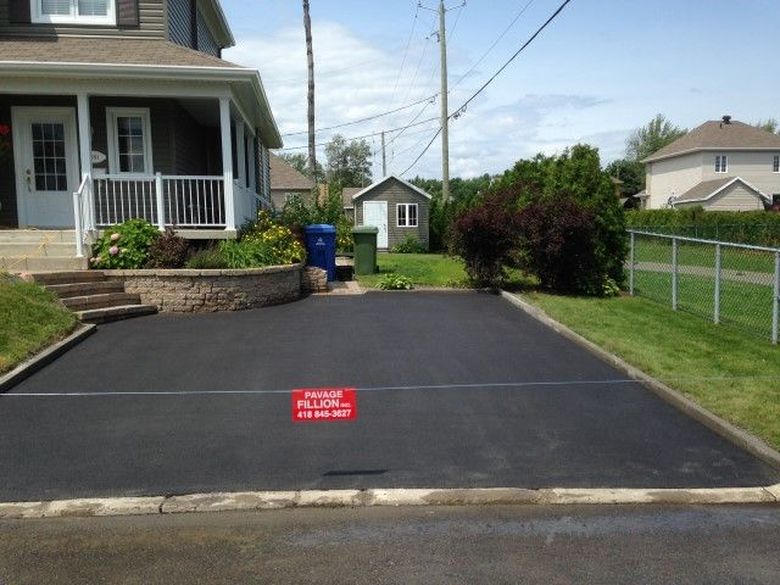 Large cour asphaltée et aménagée devant une maison