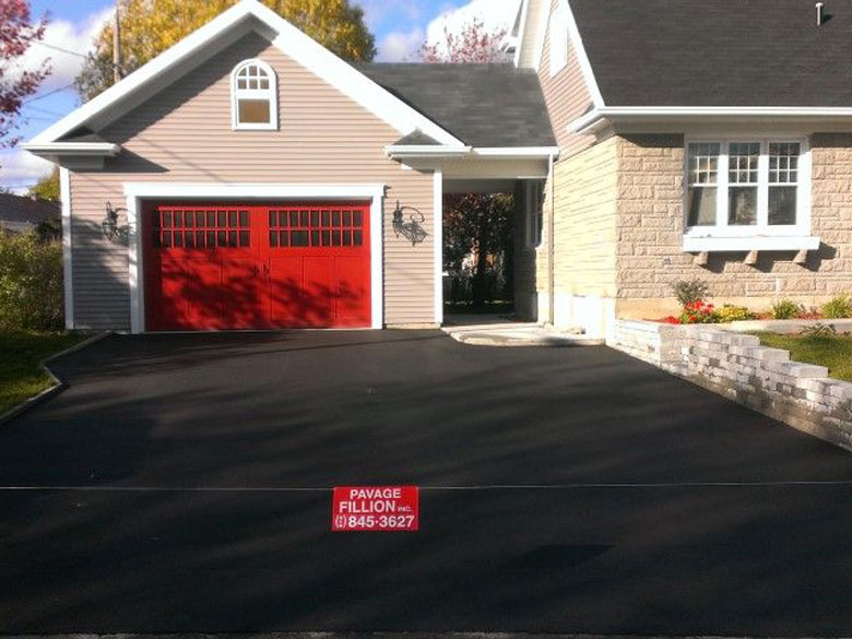 Grande entrée asphaltée devant une maison avec un garage